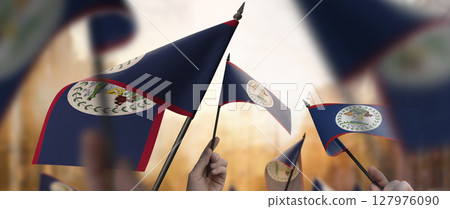 Belize flags in their hands on a blurred urban background 127976090