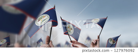 Belize flags in their hands on a blurred urban background 127976092
