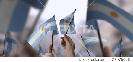 Argentina flags in their hands on a blurred urban background Argentina flags in their hands on a blurred urban background 127976098