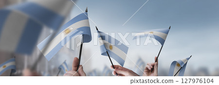 Argentina flags in their hands on a blurred urban background Argentina flags in their hands on a blurred urban background 127976104