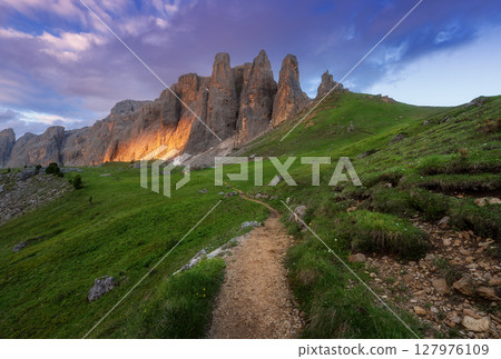Trail in alpine mountain valley with high peaks. Colorful sunset 127976109