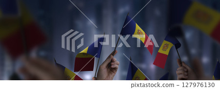 Andorra flags in their hands on a blurred urban background Andorra flags in their hands on a blurred urban background 127976130