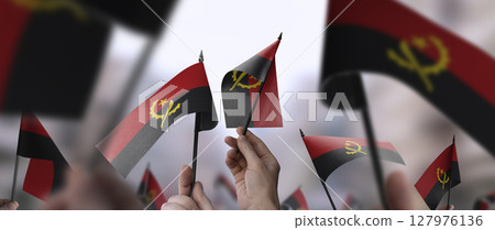Angola flags in their hands on a blurred urban background 127976136