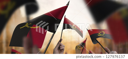 Angola flags in their hands on a blurred urban background 127976137