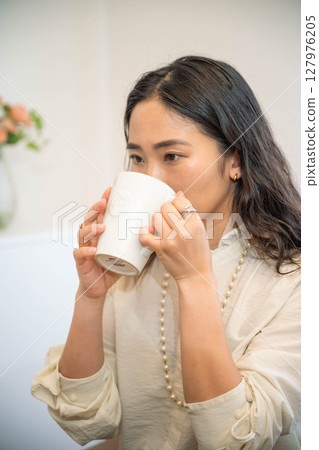 Young woman relaxing indoors and having a drink 127976205