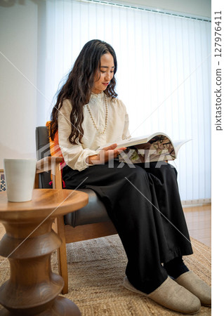 Young woman relaxing indoors reading a book Young woman relaxing indoors reading a book 127976411
