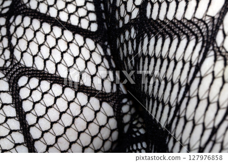 Close up of black fishnet tights on skin legs curves abstract background 127976858