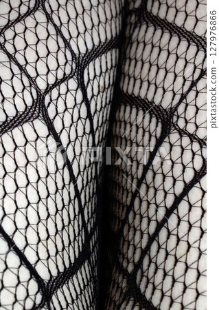 Close up of black fishnet tights on skin legs curves abstract background 127976866