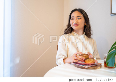 A young woman happily eating bread 127977162