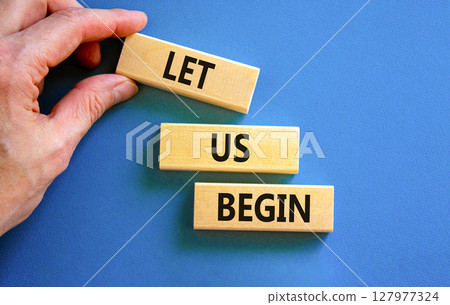 Let us begin symbol. Concept words Let us begin on beautiful wooden blocks. Beautiful blue background. Businessman hand. Business motivational let us begin concept. Copy space. 127977324