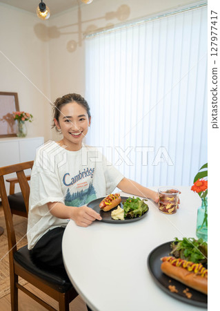 一位年輕女子在室內隨意地吃飯 一位年輕女子在室內隨意地吃飯 127977417
