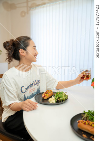 A young woman eating a meal while dressed casually indoors 127977423