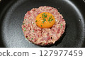 close up of raw egg and tuna tartar in a round shape on a black plate 127977459