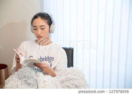 Young woman relaxing under a blanket Young woman relaxing under a blanket 127978056