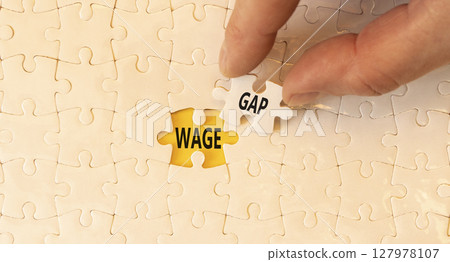 Wage gap symbol. Concept words Wage gap on beautiful white puzzles on a beautiful white background. Businessman hand. Business, support and wage gap concept. Copy space. 127978107