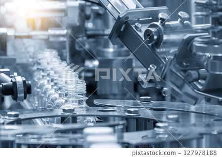 The  empty drinking water bottles on the conveyor belt for filling process in the light blue scene. 127978188