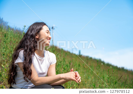 Young woman relaxing under the blue sky 127978512
