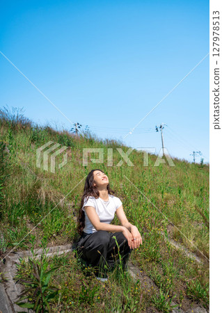 Young woman relaxing under the blue sky 127978513