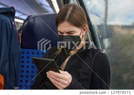 Woman on a train wearing mask and reading Woman on a train wearing mask and reading 127978571
