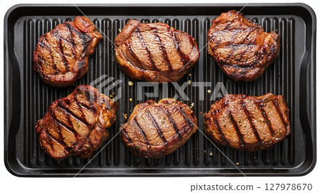 Grilled cuts of meat on a tray, marked with grill lines. Perfect for a delicious meal or a barbeque. Sizzling and ready to be enjoyed! 127978670