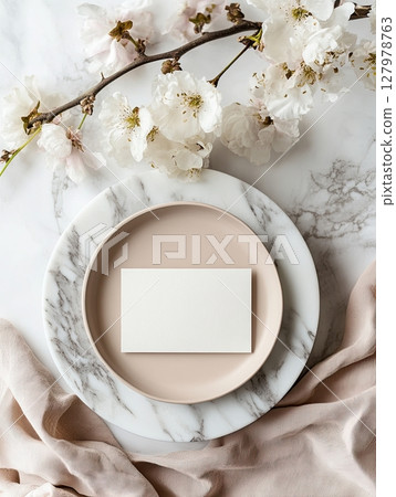 Elegant blank card on marble plate with cherry blossoms and soft fabric 127978763