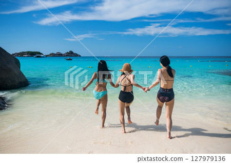 Asian friends in swimsuit run into turquoise sea at Similan island 127979136