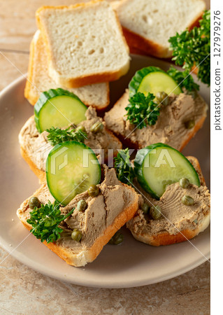 Open sandwiches with pate, cucumber, capers, and parsley. 127979276