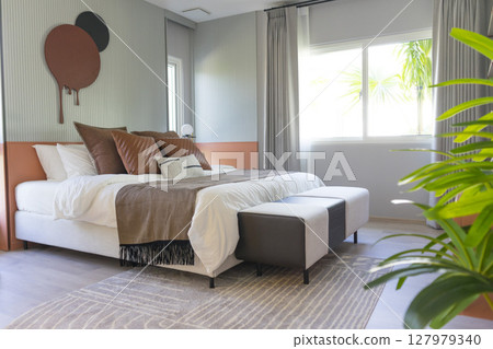 Comfortable bed with brown stylish linens and pillow with painting on wall. Interior design. Comfortable bed with brown stylish linens and pillow with painting on wall. Interior design. 127979340