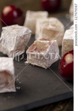 cubes of Turkish delight with the addition of dried red berries in powdered sugar closeup 127979387