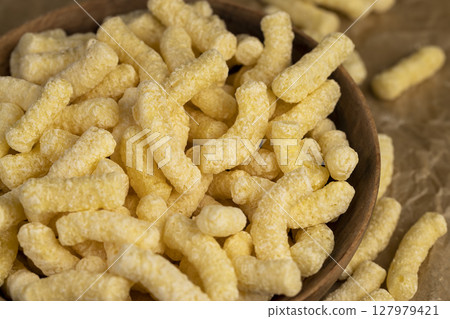 sweet corn sticks made from corn flour, a large number of ready-made corn sticks for eating or making breakfast with milk, corn sticks in a wooden bowl 127979421
