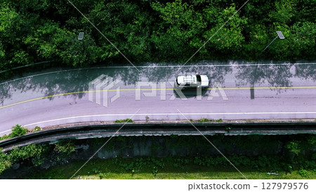 Aerial view of a road in the middle of the forest. Top view of asphalt road through forest with car adventure. Healthy environment road trip travel. Aerial view of a road in the middle of the forest. Top view of asphalt road through forest with car adventure. Healthy environment road trip travel. 127979576