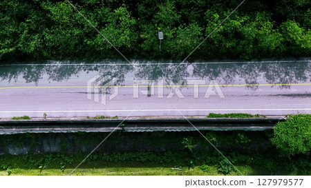 Aerial view of a road in the middle of the forest. Top view of asphalt road through forest with car adventure. Healthy environment road trip travel. Aerial view of a road in the middle of the forest. Top view of asphalt road through forest with car adventure. Healthy environment road trip travel. 127979577