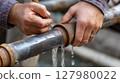 Skilled hand repairing leaking pipe outdoor 127980022