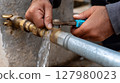 Hands repairing a water pipe and fixing a leak with tools 127980023