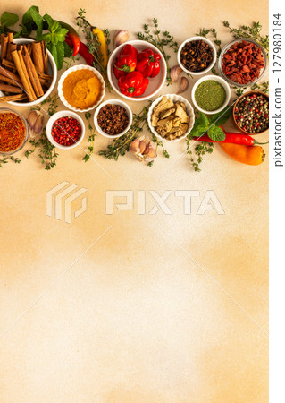 A colorful array of dried spices and fresh herbs arranged on a soft beige background, ideal for seasoning and adding rich flavor to dishes, top view and copy space 127980184