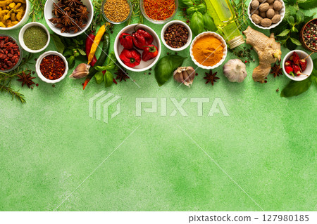 A vibrant assortment of fresh, multicolored spices and herbs on a delicate green background, perfect for cooking and culinary inspiration, top view and copy space 127980185