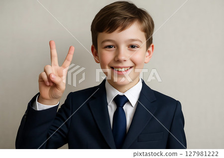 Schoolboy in uniform showing victory sign with fingers 127981222