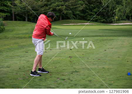 Man Swinging Golf Club on a Lush Green Course During Daylight Man Swinging Golf Club on a Lush Green Course During Daylight 127981906