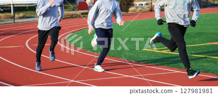 Three Runners Train on Track in Daytime Competition 127981981