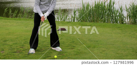 Female Golfer Preparing to Swing at a Tournament Near a Pond Female Golfer Preparing to Swing at a Tournament Near a Pond 127981996