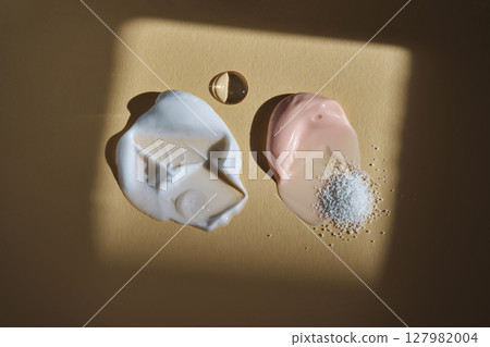 Different textures of facial cosmetics on a beige background. 127982004