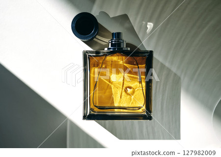 Perfume bottle in the rays of bright sun with beautiful highlights. 127982009