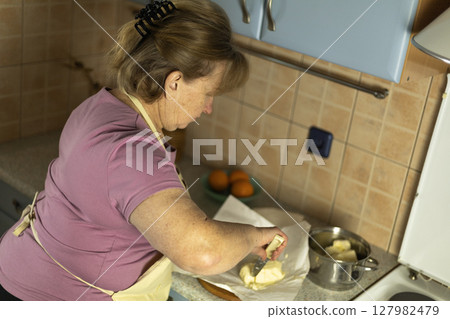 A senior woman is preparing sweet butter to make ghee. 127982479