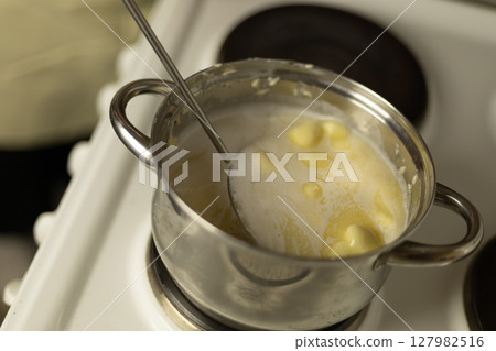 stirring sweet cream ghee with a metal spoon with holes stirring sweet cream ghee with a metal spoon with holes 127982516