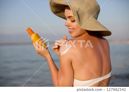 Beautiful Woman Face Portrait. Beauty Skin Care Concept. Young Woman Applying Suntan Lotion on Face. Sunscreen Solar Cream. Sun protection. The Girl Uses Moisturizer Sunblock Beauty Skin Care Concept. Beautiful Woman Face Portrait. Beauty Skin Care Concept. Young Woman Applying Suntan Lotion on Face. Sunscreen Solar Cream. Sun protection. The Girl Uses Moisturizer Sunblock Beauty Skin Care Concept. 127982542