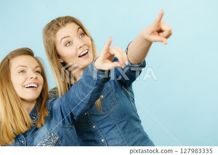 Two happy women friends wearing jeans outfit poitning Two happy women friends wearing jeans outfit poitning 127983335