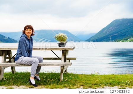 Woman tourist relax on fjord shore, Norway 127983382