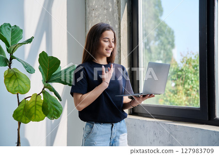 Young teenage girl using laptop for video chat conference standing at home Young teenage girl using laptop for video chat conference standing at home 127983709