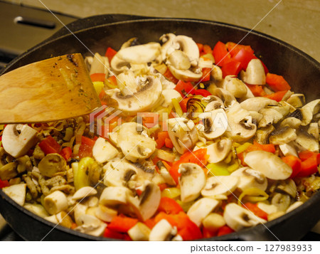Adding mushrooms to pan vegetables. 127983933