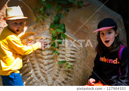 Good leisure for a child. Teaching a child through play. A handsome boy 3 oldl in a yellow jacket excavates the remains of dinosaurs. High quality photo. 127984101